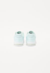 Scarpe da ginnastica di colore azzurro chiaro con una texture liscia, punta rotonda, colletto imbottito e suole in gomma bianche; presenta il logo sul retro.