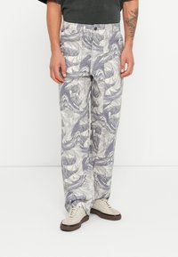 Loose-fit, patterned trousers in shades of gray and cream, featuring a wave design. Made from lightweight fabric with a button closure.