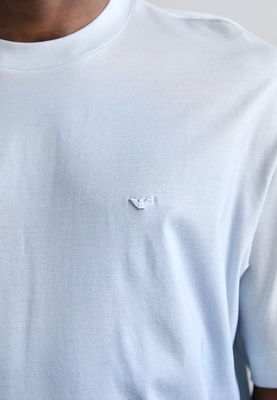 Ανοιχτό μπλε βαμβακερό t-shirt με στρογγυλή λαιμόκοψη, που διαθέτει ένα μικρό κεντητό λογότυπο στο αριστερό στήθος. Μαλακή υφή και άνετη εφαρμογή.