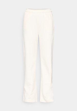 Kremske boje trenirka s elastičnim pojasom, ravnim krojem nogavica, mekanom teksturom i bočnim džepovima. Bez vidljivih uzoraka ili naglasaka.