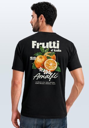 Man facing away wears black t-shirt with graphic of oranges, green leaves, white flowers, and text about Italian fruit and Amalfi.