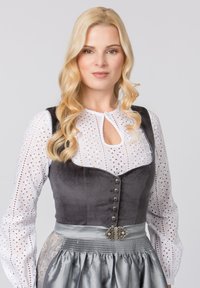 Traditionelles Kleid mit einem taillierten schwarzen Samtmieder mit silbernen Knöpfen, darüber eine weiße Broderie Anglaise-Bluse und einem satin-silbernen Rock.