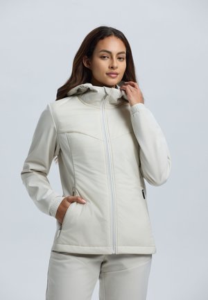 Lichte beige jas met een hoge kraag, ritssluiting en zijzakken. Gladde textuur met subtiele stikseldetails.