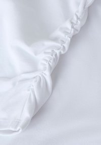 Tejido de algodón blanco con textura fruncida, que presenta una superficie suave y lisa con un ligero brillo. Las costuras están bien acabadas.