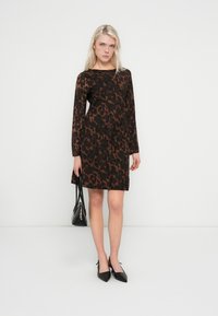 Rochie cu mâneci lungi cu imprimeu leopard maro, croială dreaptă, țesătură texturată; asortată cu pantofi negri cu vârf ascuțit și o geantă mică neagră.