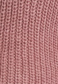 Gebreide stof in een zachte roze tint met een opvallend, textuurgegeven garenpatroon. De steken creëren een geribd ontwerp, waarmee de diepte en zachtheid ervan worden benadrukt.