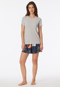 Camicetta grigia chiara a maniche corte abbinata a pantaloni corti navy con motivo floreale e dettagli arancioni, realizzati in tessuto morbido e con vestibilità rilassata.