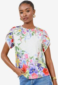 Maglietta a maniche corte floreale caratterizzata da un mix di fiori colorati su uno sfondo chiaro, con dettagli in pizzo sulle spalle e una vestibilità comoda.