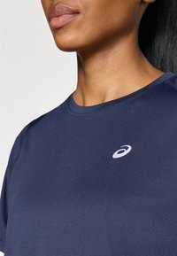 Ναυτικό μ πλε αθλητικό μπλουζάκι με στρογγυλή λαιμόκοψη, κοντά μανίκια και διακριτική λογότυπη λεπτομέρεια στο στήθος. Υφασμάτινη υφή.