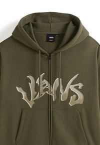 Hoodie zippé vert olive avec un grand logo graphique blanc sur la poitrine, doublure en polaire à l'intérieur, capuche avec cordon de serrage et poches avant.
