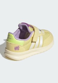 Yellow sneaker with silver stripes, purple accents, and green heel detail. Features a velcro strap and textured fabric. Crown design on the heel.