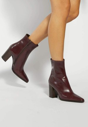 Burgundy leather ankle boots with a pointed toe and a side zipper, featuring a textured block heel and a smooth finish.