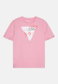 Pink cotton t-shirt featuring a triangular graphic with the brand name "GUESS," question mark, and text "WASHED JEANS" in black and white.