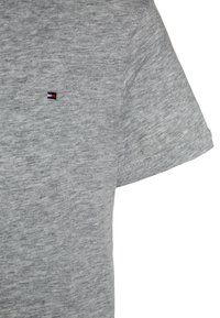 Maglietta grigia a maniche corte realizzata in morbido cotone, con un piccolo logo ricamato in rosso, bianco e blu sul lato sinistro del petto.