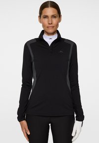 Schwarzer Pullover mit langen Ärmeln und halb verdecktem Reißverschlusskragen, mit grauen Akzenten auf den Schultern, aus einem glatten, dehnbaren Material.