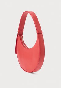 Czerwona skórzana torebka na ramię o zakrzywionym kształcie, gładkiej fakturze i złotym zamku błyskawicznym. Pasek jest płaski i regulowany dla komfortu.