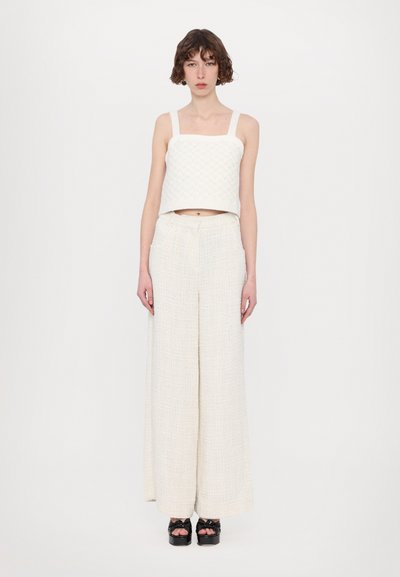 White cropped top with square neckline and textured fabric, paired with wide-leg cream trousers featuring subtle weave patterns and pockets.