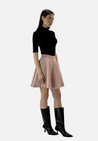 Maglione nero a maniche corte con collo a dolcevita, gonna rosa svasata e stivali neri fino al ginocchio. Materiale morbido con silhouette aderente e texture sottile.