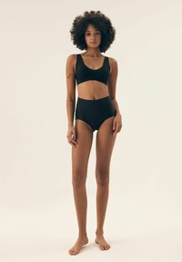 Black two-piece swimwear set featuring a bralette top with a scoop neckline and high-waisted bottoms with cut-out detailing. Smooth texture.