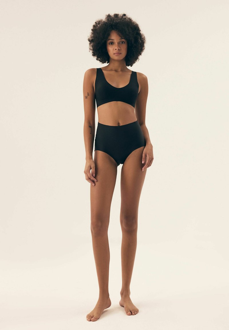 Black two-piece swimwear set featuring a bralette top with a scoop neckline and high-waisted bottoms with cut-out detailing. Smooth texture.
