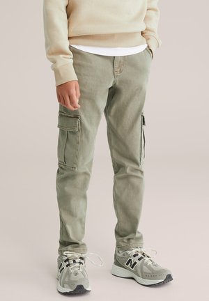 Pantalones cargo en verde claro, fabricados en una mezcla de algodón, con bolsillos laterales, un corte relajado y zapatillas grises coordinadas con acentos blancos.