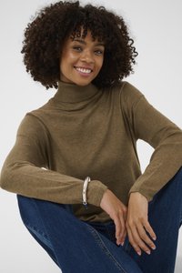 Brauner, gerippter Rollkragenpullover mit weicher Textur und enganliegenden Ärmeln, kombiniert mit blauen Jeans. Ein silbernes Armband schmückt das Handgelenk.