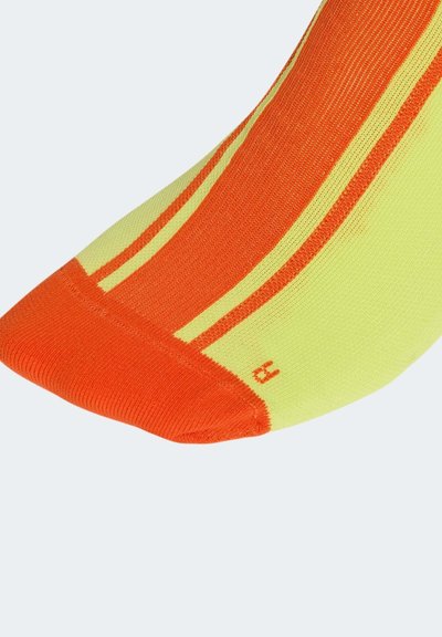 Calcetines hechos de tela amarilla y naranja con rayas. La sección del dedo del pie es de color naranja con un acabado liso y un pequeño detalle del número "3".