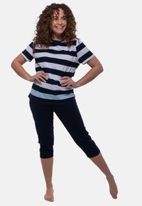 Lyhyet hihattamat raidalliset paidat tummansinisessä ja vaaleansinisessä, yhdistettynä tummansinisiin caprihousuihin. Pehmeä kangas, rento istuvuus, minimaalinen tekstuuri ja ei näkyviä yksityiskohtia.