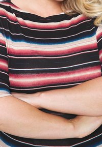Černý top s vodorovnými pruhy v červených, růžových a modrých odstínech. Má kulatý výstřih a krátké rukávy, vyrobený z měkkého, elastického materiálu.