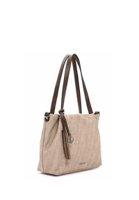 Sac fourre-tout en tissu beige avec des anses en cuir marron, orné d'un pompon et d'un logo métallique. Forme rectangulaire avec une texture douce.