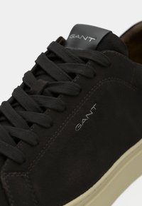 Schwarze Wildleder-Sneaker mit runder Zehenpartie, flachen schwarzen Schnürsenkeln, brauner Gummisohle und "GANT"-Logo auf der Zunge und der Seite. Subtile Nähdetails.