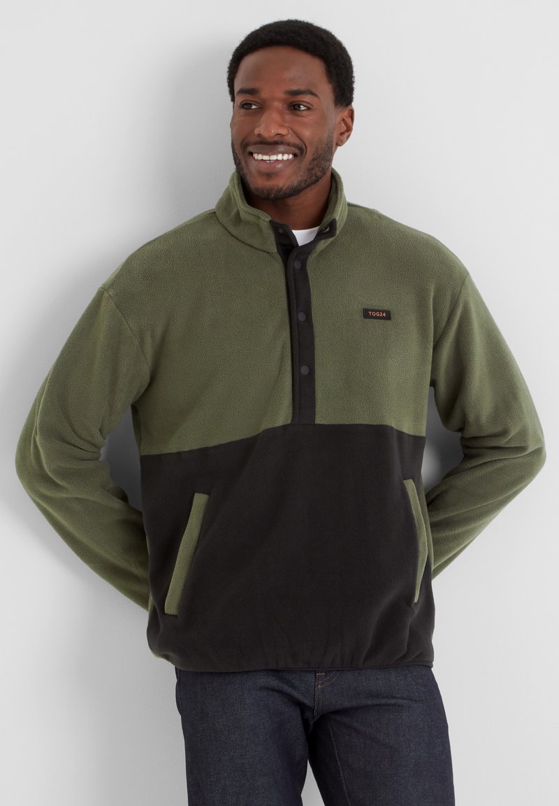 Fleece pullover in olive green with black lower section, half-zip design, button accents, and front pockets. Soft texture, casual fit.