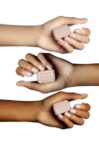 Trois mains tiennent des flacons de vernis à ongles Essie. Le vernis est d'une couleur nude crémeuse et claire. Chaque main a des ongles soigneusement manucurés dans des nuances assorties.