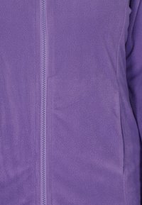 Giacca in pile viola con zip a lunghezza completa, superficie testurizzata e tessuto liscio, dal design aderente.