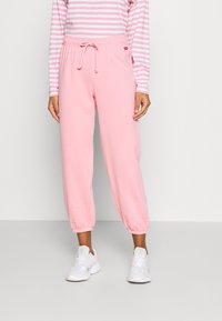 Pink sweatpants with an elastic waistband and drawstring; cuffed ankles; paired with a long-sleeve, white and pink striped top.