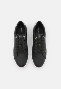 Paire de baskets basses noires avec semelles blanches, lacets noirs et semelles intérieures de marque, vues de dessus sur fond blanc.
