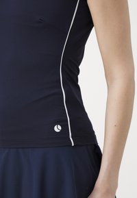 Ναυτικό αθλητικό κοντομάνικο μπλουζάκι με λευκές ρίγες στα πλάγια, εφαρμοστό σχέδιο και μικρό λογότυπο στην κάτω αριστερή γωνία. Λείος υφασμάτινος χαρακτήρας.