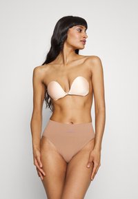 Beige klisterbh med et glat, formet design. Højtaljede nude trusser med et diskret Adidas-logo på taljebåndet.