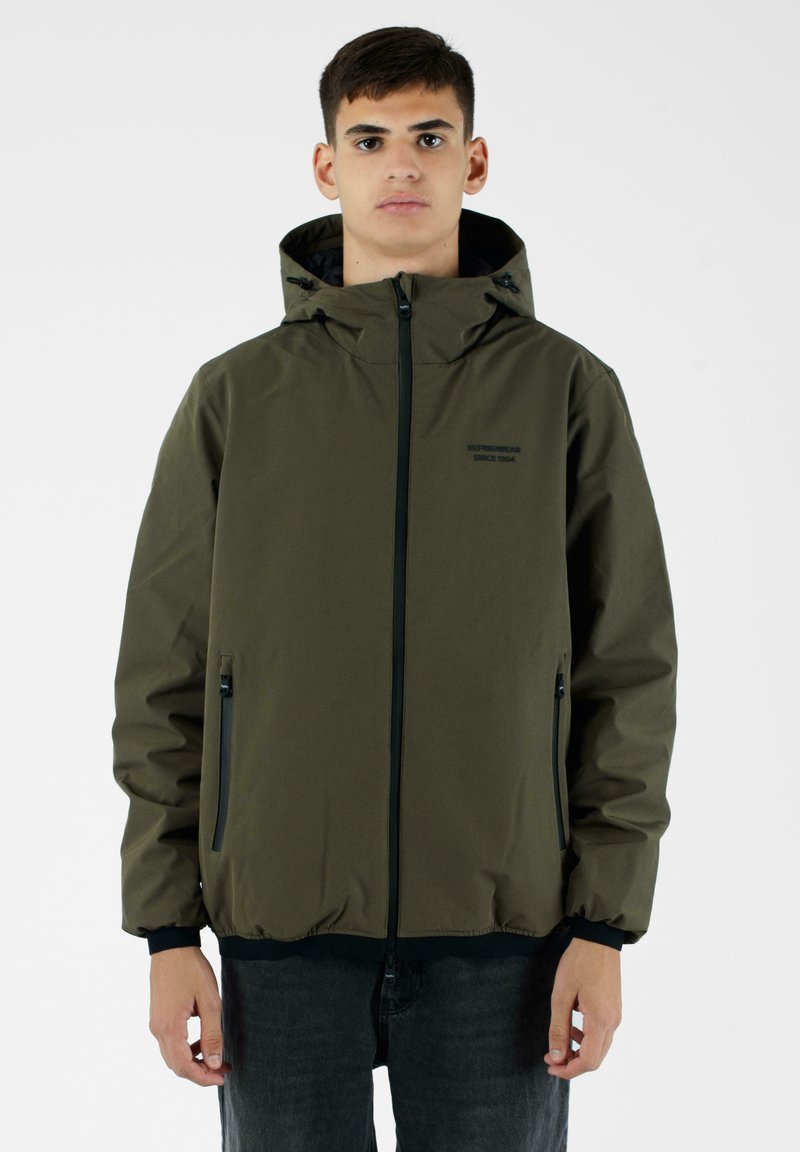 Giacca impermeabile verde oliva con cappuccio, cerniera frontale e due tasche laterali. Presenta dettagli neri e un design a vestibilità ampia.