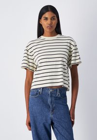 Camiseta recortada en un beige claro con rayas horizontales marrón oscuro. Presenta mangas cortas y un cuello acanalado, confeccionada en suave material de algodón.