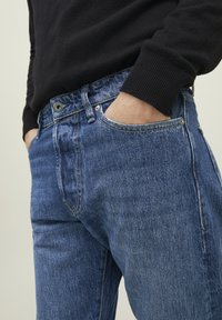 Blå denimjeans med en klassisk passform, med framlommer, metallknappstängning och lätt blekning för struktur.