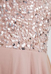 Sukienka z brzoskwiniowym tiulowym gorsetem ozdobionym cekinami i perłami, charakteryzująca się teksturowaną powierzchnią i dopasowanym krojem.