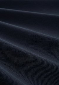Dunkelblauer Stoff mit glatter Textur, der subtile gerippte Muster und weiche, fließende Falten aufweist. Geeignet für verschiedene Textilanwendungen.