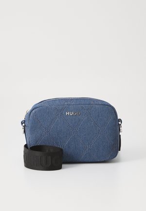 Blaues Denim-Crossbody-Bag mit gesteppter Musterung, silbernem Beschläge und schwarzem Logo-Gurt. Rechteckige Form mit Reißverschluss oben.