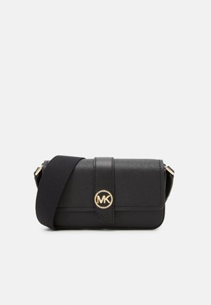 Zwarte crossbodytas met verstelbare brede riem, gouden MK-logo sluiting en klepsluiting op een effen achtergrond.