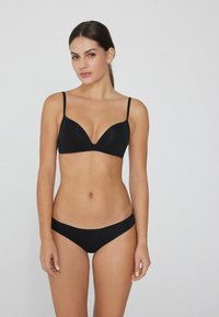 Schwarzes BH- und Bikini-Set mit V-Ausschnitt-Design, verstellbaren Trägern und nahtloser Textur für Komfort und minimale Sichtbarkeit.