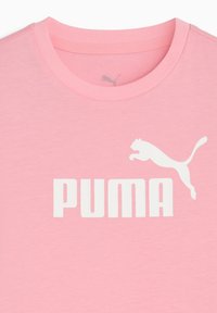 Jasnoróżowa koszulka z dużym białym logo "PUMA" oraz sylwetką skaczącego pumy. Prosty krój z okrągłym dekoltem.