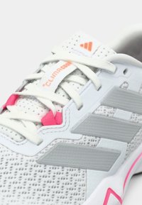 Scarpa sportiva bianca con tomaia in mesh, strisce grigie, dettagli rosa e sistema di allacciatura bianco. Presenta il marchio "ClimaCool" sulla parte superiore.