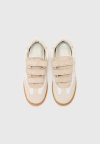 Des baskets avec une palette de couleurs beige et blanche, dotées d'une tige en suède lisse, de sangles en tissu texturé et de semelles en caoutchouc gomme.