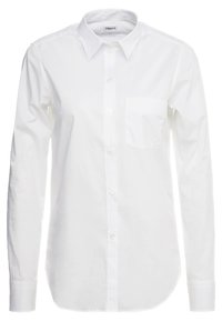 Camicia bianca a maniche lunghe con bottoni, realizzata in cotone, con colletto classico, una singola tasca sul petto e una finitura liscia e testurizzata.